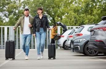 Happy people walking with luggage off of the parking lot