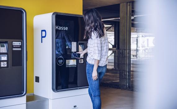 Frau steht vor Kassenautomat