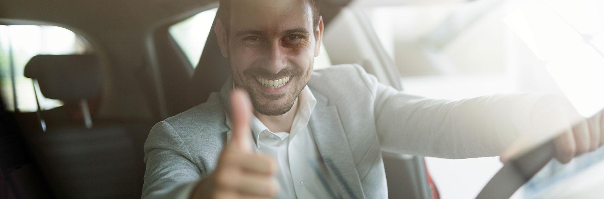 Man sitzt im Auto und zeigt den Daumen hoch